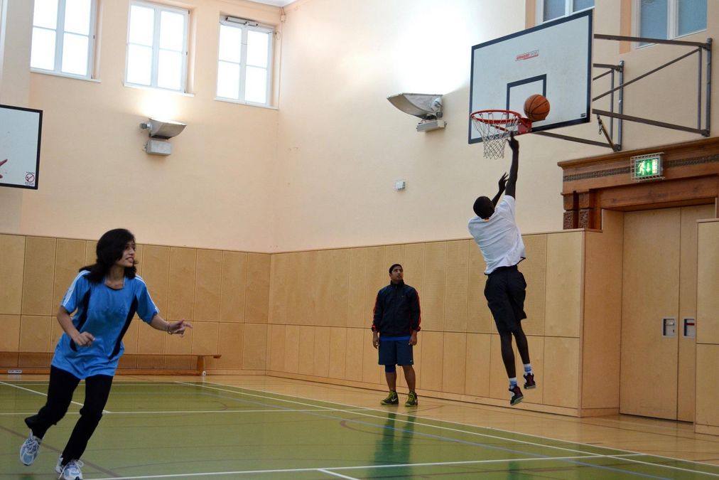 zur Vergrößerungsansicht des Bildes: Drei Personen im Basketballtraining, ein Spieler führt einen Korbleger aus.