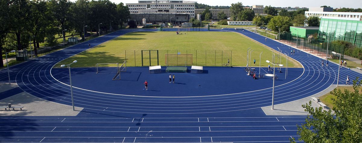 zur Vergrößerungsansicht des Bildes: Foto: Sportstätte mit in blau gehaltener Laufbahn 