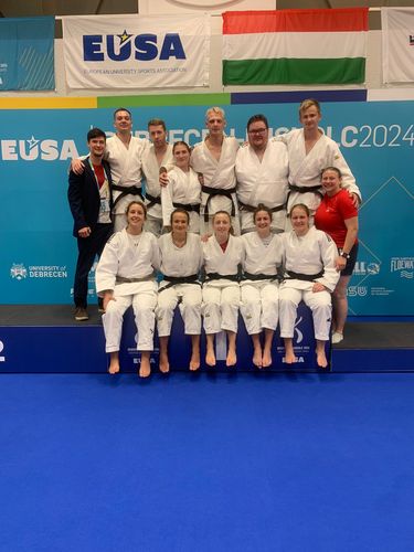 Menschengruppe mit weißen Kampfsportanzügen kommen für ein Gruppenfoto zusammen