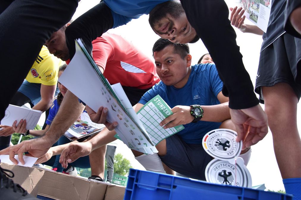 Mehrere Teilnehmer einer Fußballgruppe verteilen Werbematerial aus einem Karton.