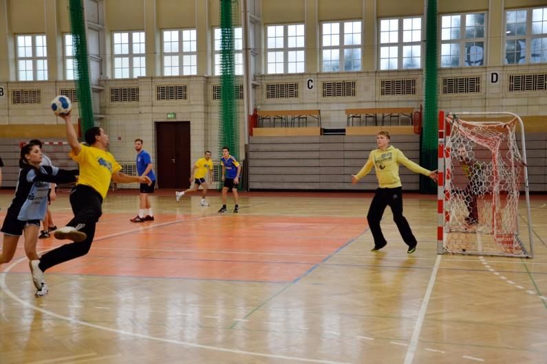 Eine Handballszene mit Torwurf und Abwehrhaltung des Torhüters.
