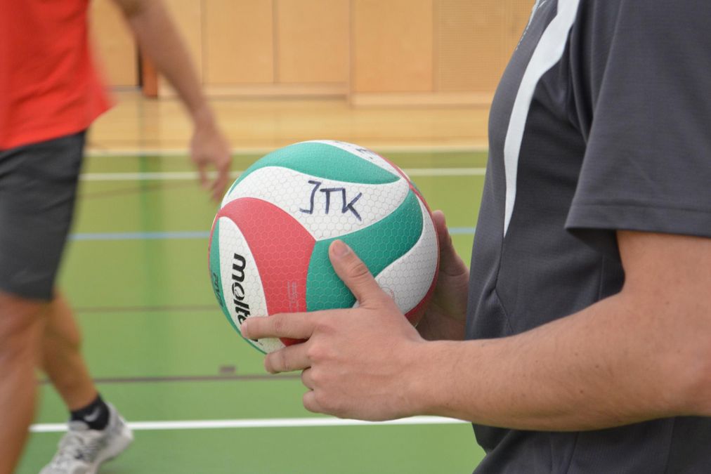 ein Student hält einen Volleyball mit der Aufschrift ITK