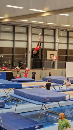 Eine Person springt in einer Turnhalle auf einem Trampolin.