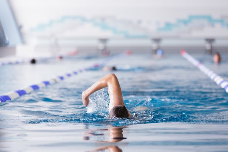 Frontaler Blick auf eine Schwimmbahn in der ein Student gerade krault, Foto: Christian Hüller