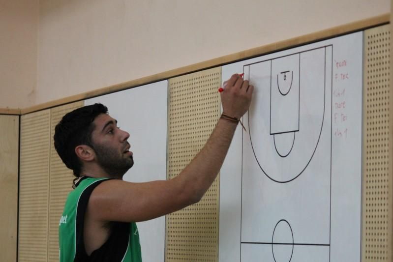 Ein Basketballer steht an der Hallenwand am Taktikboard und zeichnet eine Szene darauf.