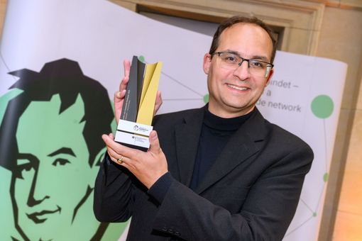 Professor Daniel Kráľ mit einer Art Pokal der Humboldt-Stiftung in den Händen.