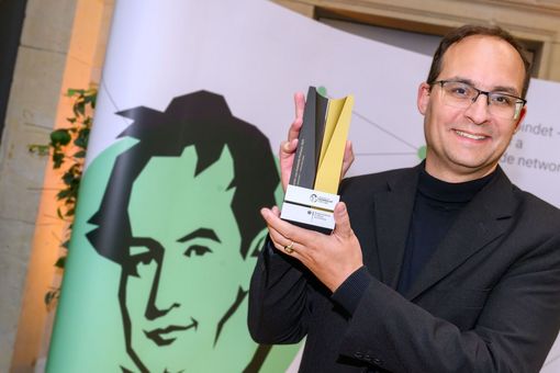 Professor Daniel Kráľ mit einer Art Pokal der Humboldt-Stiftung in den Händen.