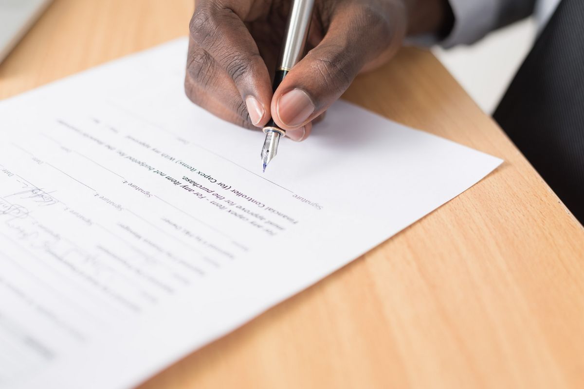 zur Vergrößerungsansicht des Bildes: Hand of a person holding a pen to sign paperwork