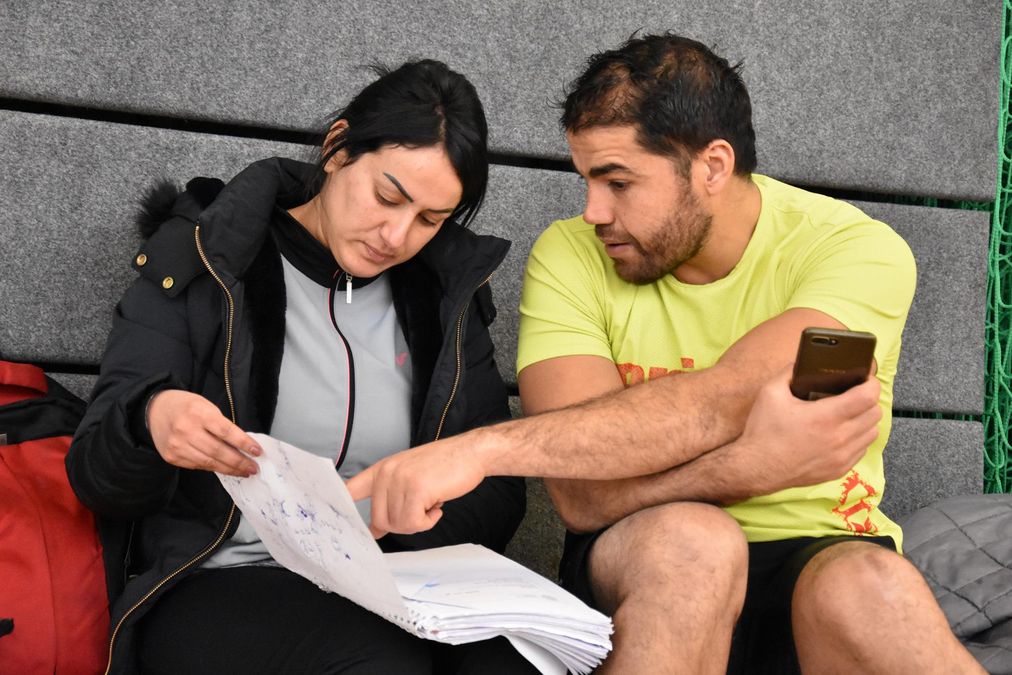 zur Vergrößerungsansicht des Bildes: Ein Teilnehmer und eine Teilnehmerin besprechen ein Problem auf der Bank in der Halle.