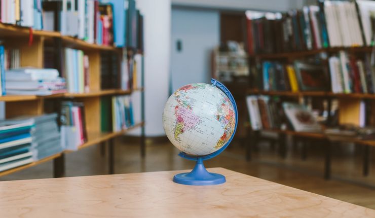 Auf einem Tisch in einer Bibliothek steht ein kleiner Globus. Er steht für die ganzheitlichen Ansatz der Forschung.