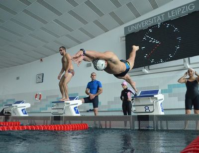 Ein Schwimmer in der Flugphase eines Startsprungs vom Block