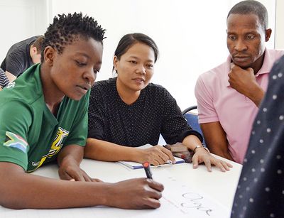 on the photo you see students in a classroom working together in small groups