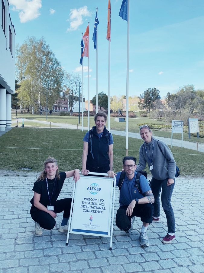 zur Vergrößerungsansicht des Bildes: Mitarbeitende der Professur Sportdidaktik/ Bewegungspädagogik posieren auf der AIESEP 2024 International Conference in Jyväskylä, Finnland vor einem Aufsteller. 