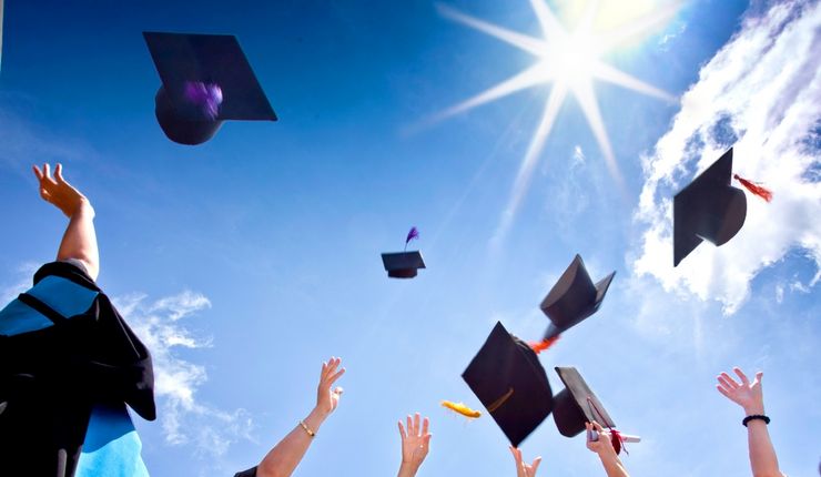 Zur Feier ihres Abschlusses werfen Studierende ihre Absolventenhüte in die Luft