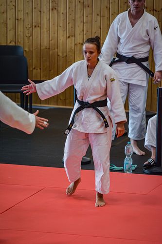 Eine Frau steht im weißen Kampfsportanzug im Mittelpunkt.