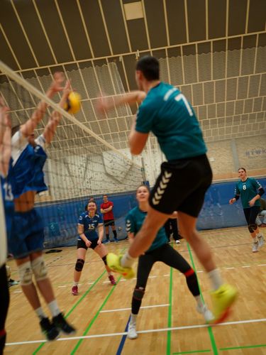Es ist ein Volleyball Feld von der Seite zu sehen und eine Person macht ein Angriffsschlag.