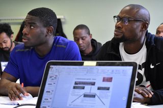 Zwei Studierende sitzen aufmerksam im Theorieseminar hinter einem Computer